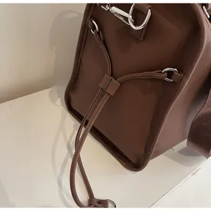 Detail shot of a dark brown PU leather tote bag with silver rings and adjustable straps