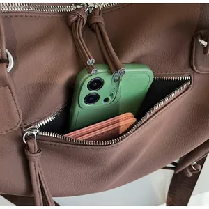 Detail of dark brown pebbled leather bag with silver zipper pocket and phone compartment