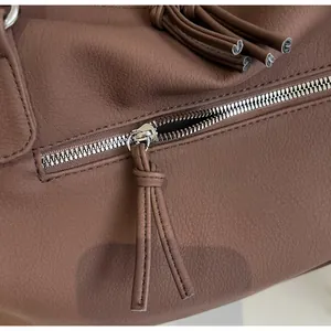 Detailed macro view of the smooth silver metal zipper and brown pebbled leather texture