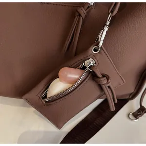 Detail of coffee brown textured bag with detachable pouch and silver zipper showing lipstick