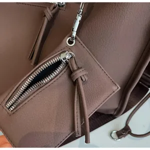 Close-up of smooth silver metal zipper and lychee textured leather on a brown tote bag