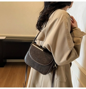 Detail of vintage dark brown leather saddle bag with flap and adjustable shoulder strap