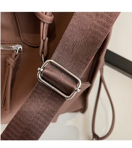 Detail view of adjustable brown woven shoulder strap with polished silver metal buckle