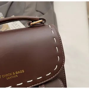 Detail of dark brown leather bag showing white contrast stitching and gold metal hardware