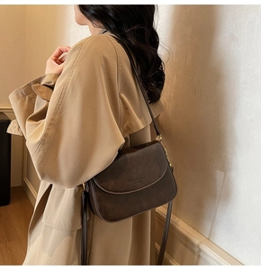 Close-up of a vintage dark brown saddle bag with embossed FASHION & BAGS lettering