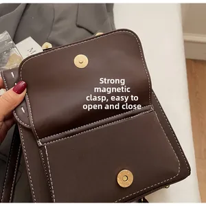 Detail view of dark brown leather bag showing dual gold magnetic buckles and contrast stitching