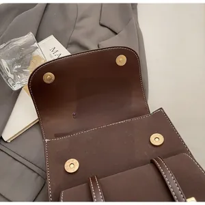 Detail of dark brown vintage backpack featuring gold magnetic clasp and contrast stitching