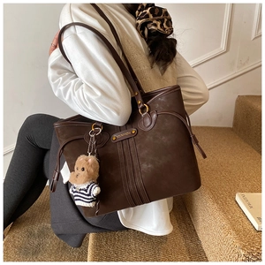 Detail of coffee brown matte tote bag with vertical stitching and cute bear charm