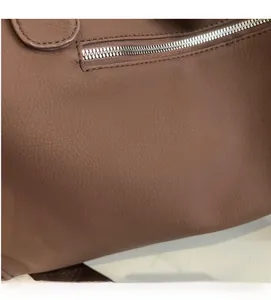 Close-up of brown litchi pattern leather texture and silver metal zipper detail