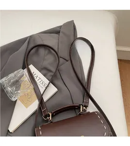 Close-up of vintage brown leather bag with white contrast stitching and gold hardware