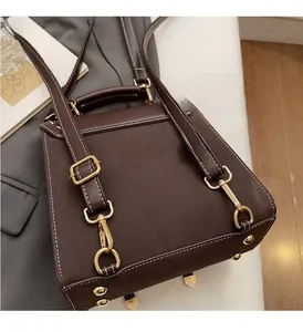 Detail of vintage brown leather backpack featuring gold metal buckle and white stitching