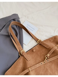 Vue détaillée du sac cabas marron présentant une texture daim et une boucle dorée