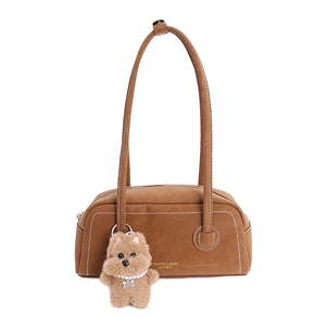 Brown leather shoulder bag with white contrast stitching and a small plush dog charm