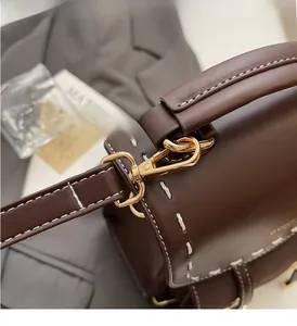 Detail of brown leather backpack with gold hardware hooks and white contrast stitching