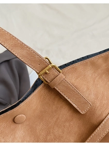 Gros plan du sac cabas marron avec surpiqûres blanches et boucle métallique dorée chic