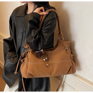 Dettaglio borsa tote color caramello con cuciture a contrasto e ciondolo a cuore