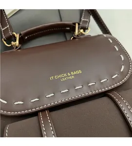 Detail of dark brown leather backpack showing contrast stitching and gold branding