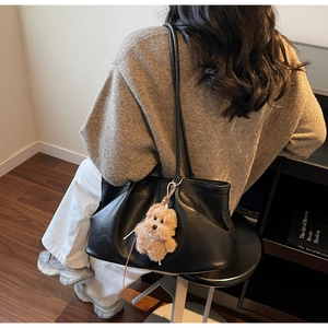 Détail d'un grand cabas noir souple avec bretelles et un petit pendentif chien en peluche