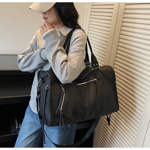 Close-up of black large capacity travel tote bag with adjustable shoulder strap and pouch