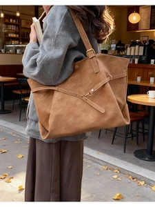 Détail de la texture en similicuir marron mat et de la boucle métallique d'un sac cabas