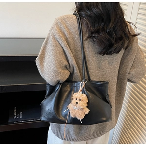 Détail du grand sac cabas en cuir souple noir avec un charmant pendentif en peluche