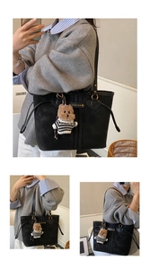 Detailed view of black tote bag with metal ring handle and plush bear charm accessory
