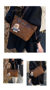 Detail of vintage brown suede tote bag with logo plaque and cute plush bear charm