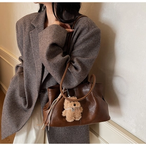 Détail d'un cabas en cuir ciré marron foncé avec ours en peluche et pompon décoratif