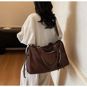 Detail of dark brown oversized travel tote bag with reinforced handles and mini pouch