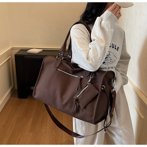 Detail of dark brown leather travel tote bag with shoulder strap and mini coin purse