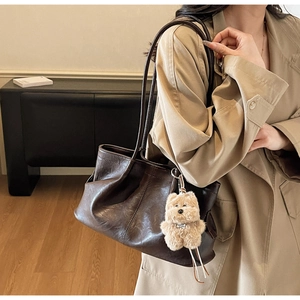 Détail d'un sac cabas en cuir marron vintage avec un adorable charm en peluche pour chien