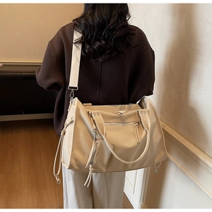 Detail showing creamy white large tote bag with zipper pocket and wide woven strap