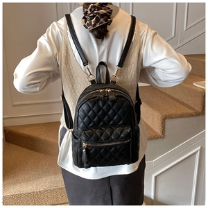 Détail d'un mini sac à dos matelassé noir avec fermetures éclair dorées chic