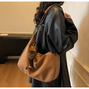 Detail of vintage brown suede hobo bag with plush ball and wooden bead charm accessories