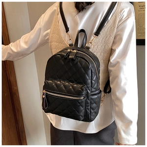 Detail of a black quilted mini backpack with gold hardware worn by a model