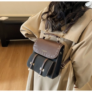 Detail of vintage contrast leather backpack with stitching on model in beige trench coat