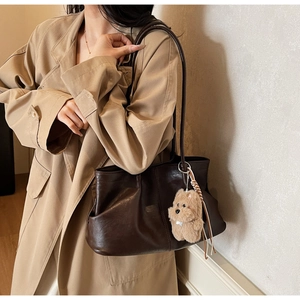 Détail du sac cabas en cuir marron foncé avec breloque chien sur trench beige