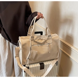 Detail of minimalist beige travel tote bag with small coin purse on a striped suitcase