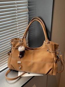 Grande borsa tote in pelle marrone con cuciture a croce bianche e ciondolo morbido