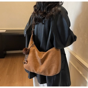 Detail of vintage suede shoulder bag in caramel brown with plush charm and bead accessory