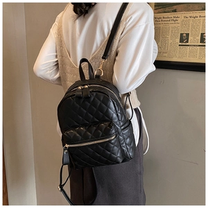 Close-up of black quilted PU leather backpack with gold zippers and stylish stitching