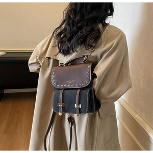 Detail of vintage patchwork backpack with gold buckles on a khaki trench coat