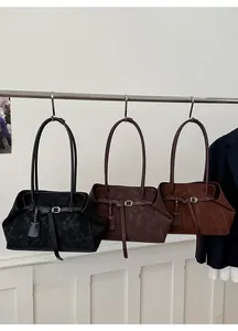 Close-up of three suede tote bags in black, dark brown, and caramel with strap buckles