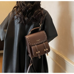 Detail of vintage brown leather backpack with white stitching and brand logo