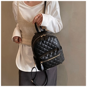 Detail of black quilted mini backpack with gold hardware and classic rhombus stitching