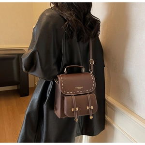 Detail of dark brown leather backpack with contrast stitching and gold metal hardware