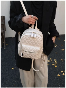 Detailed view of white quilted mini backpack with gold hardware and PU leather texture