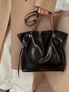 Sac fourre-tout noir à cordon avec chaîne dorée, porté par un mannequin en manteau