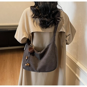 Detail of retro suede tote bag with contrast stitching and ethnic plush charm decoration