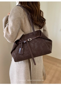 Detail of dark brown suede-like tote bag with metal buckle and retro minimalist design